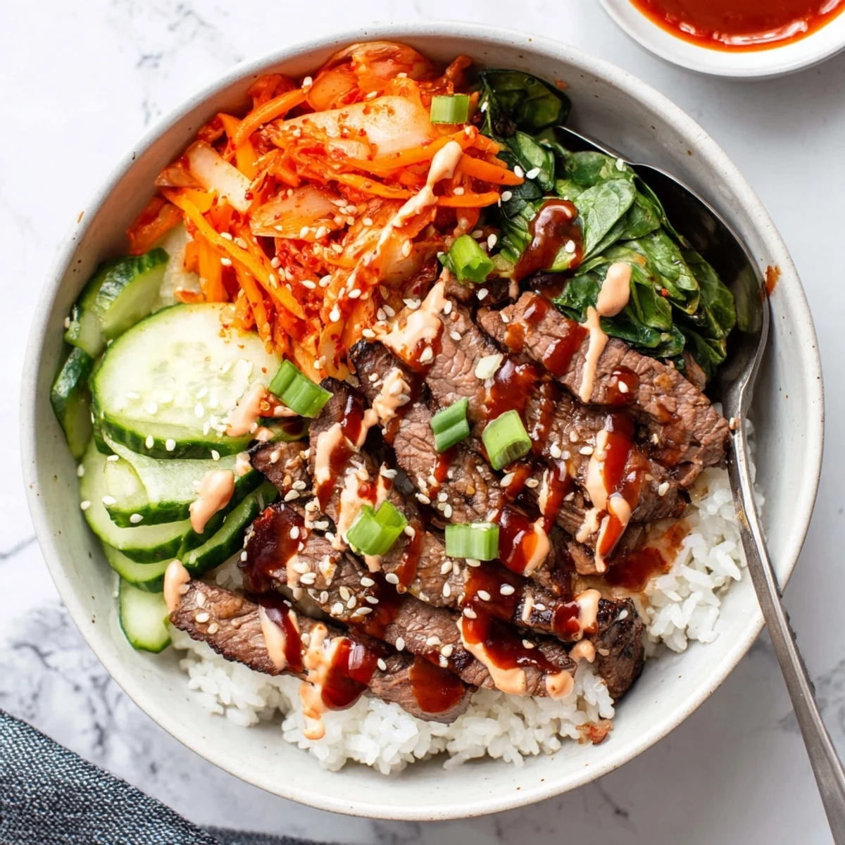 Sizzling gochujang-glazed steak arranged over greens and rice in a vibrant Korean BBQ steak rice bowl with spicy cream sauce