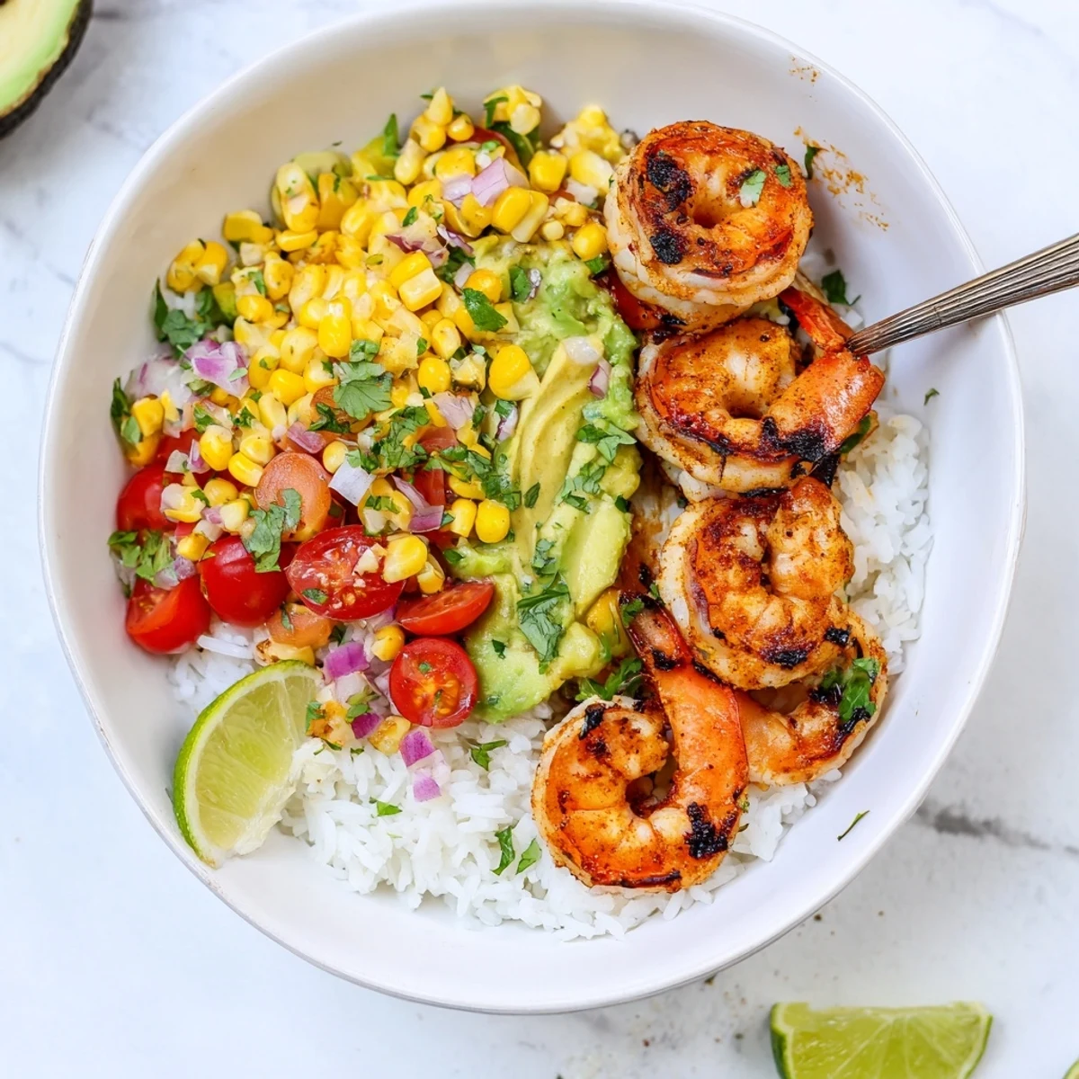 Grilled shrimp bowl with avocado corn salsa topped with fresh lime wedges