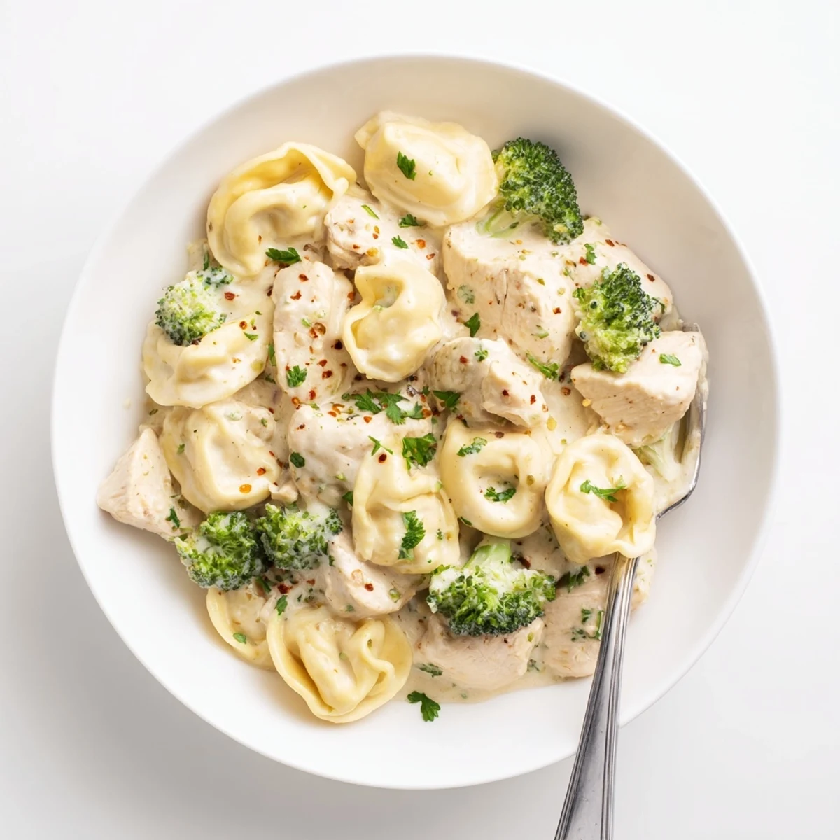 Bowl of Creamy Garlic Parmesan Tortellini Chicken Broccoli with tender bites, silky sauce.