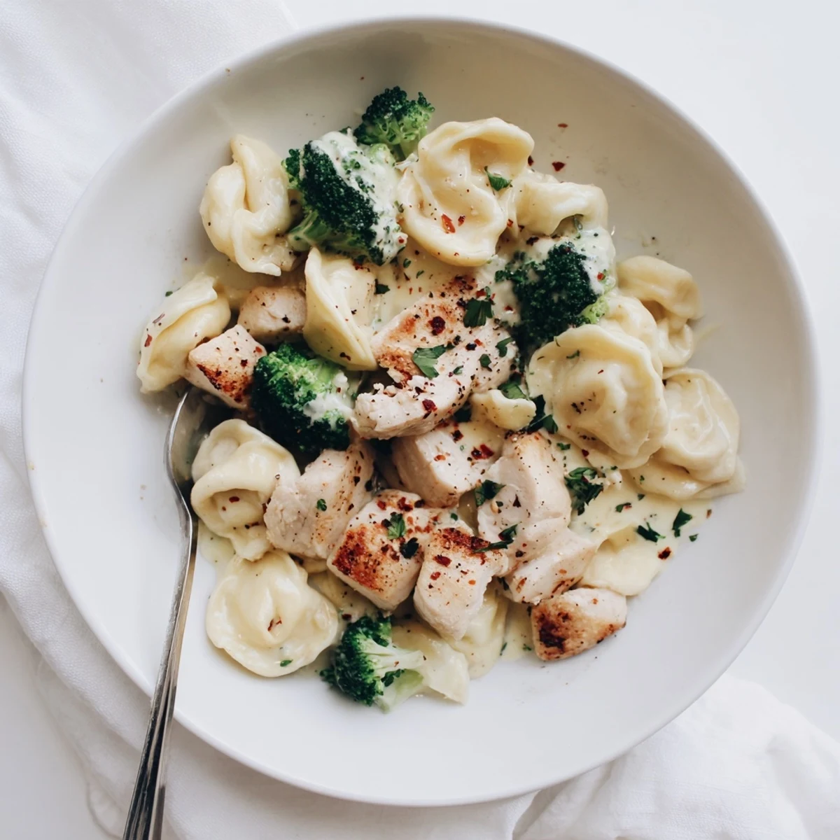 Skillet of Creamy Garlic Parmesan Tortellini Chicken Broccoli, golden chicken and aromatic garlic.