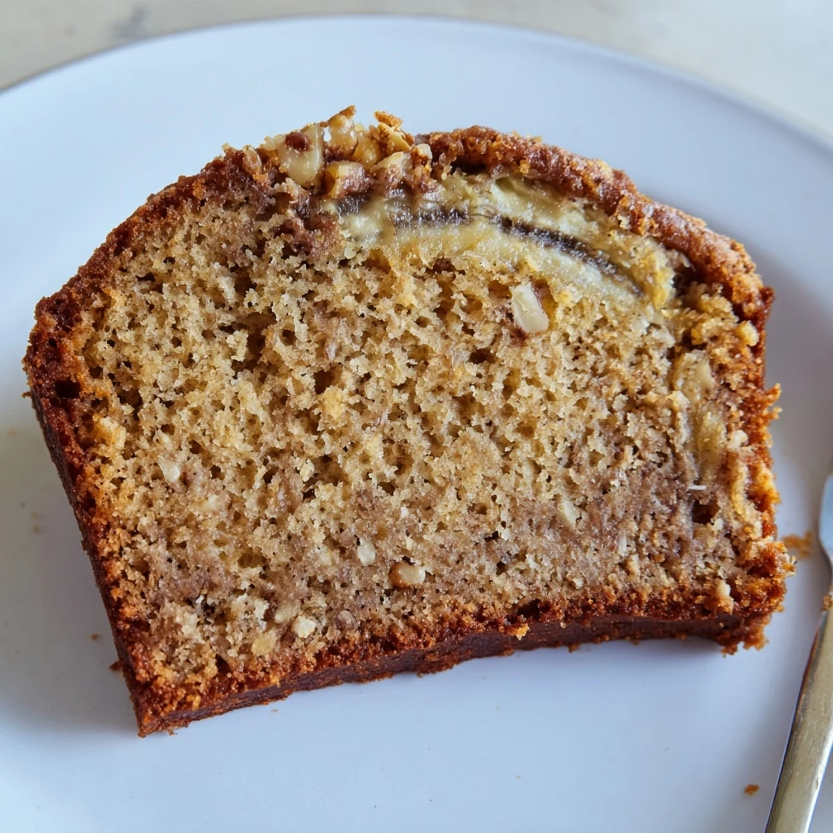Moist Banana Bread Cake Recipe studded with walnuts, cinnamon scent, breakfast-ready.
