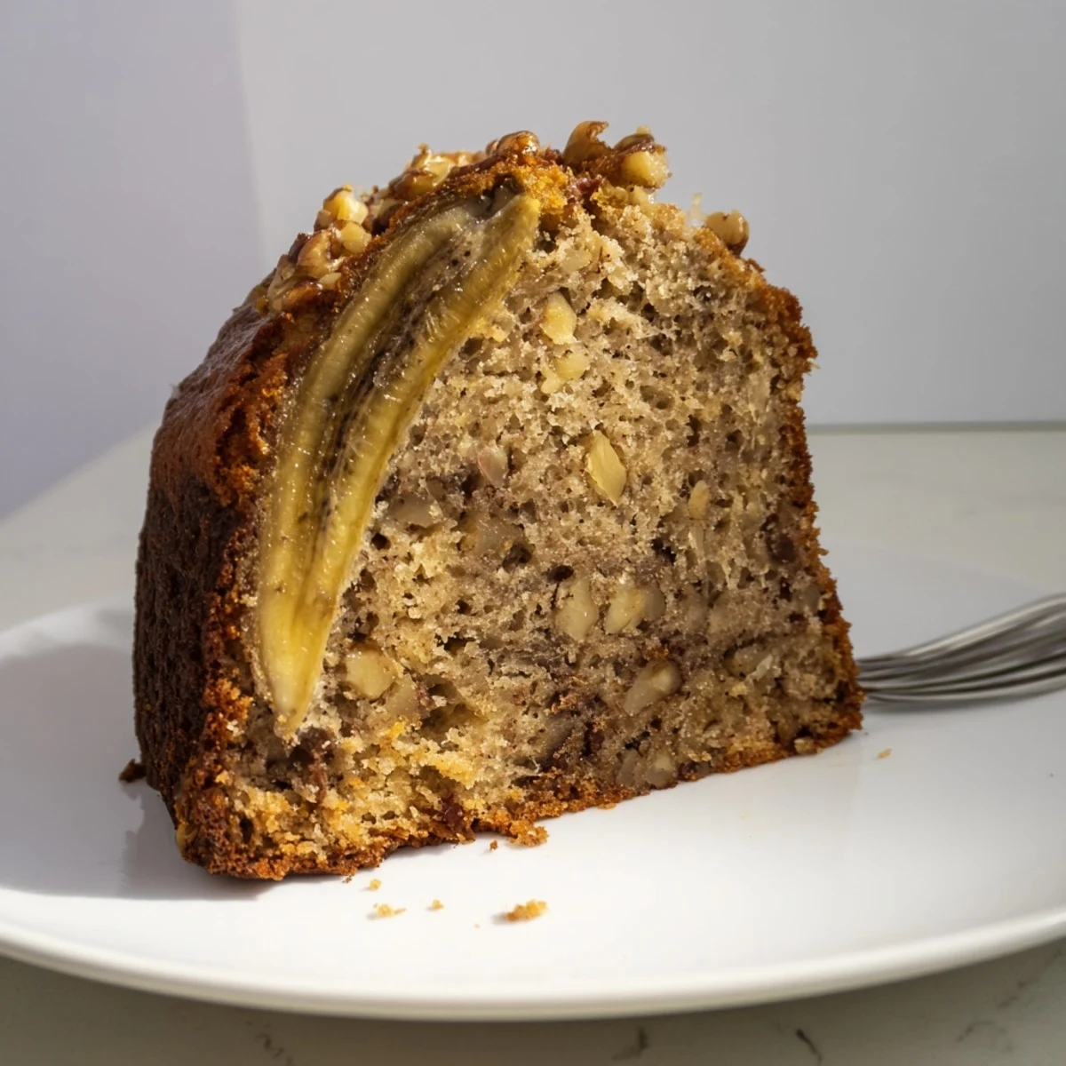 A slice of Banana Bread Cake Recipe served with melting vanilla ice cream.