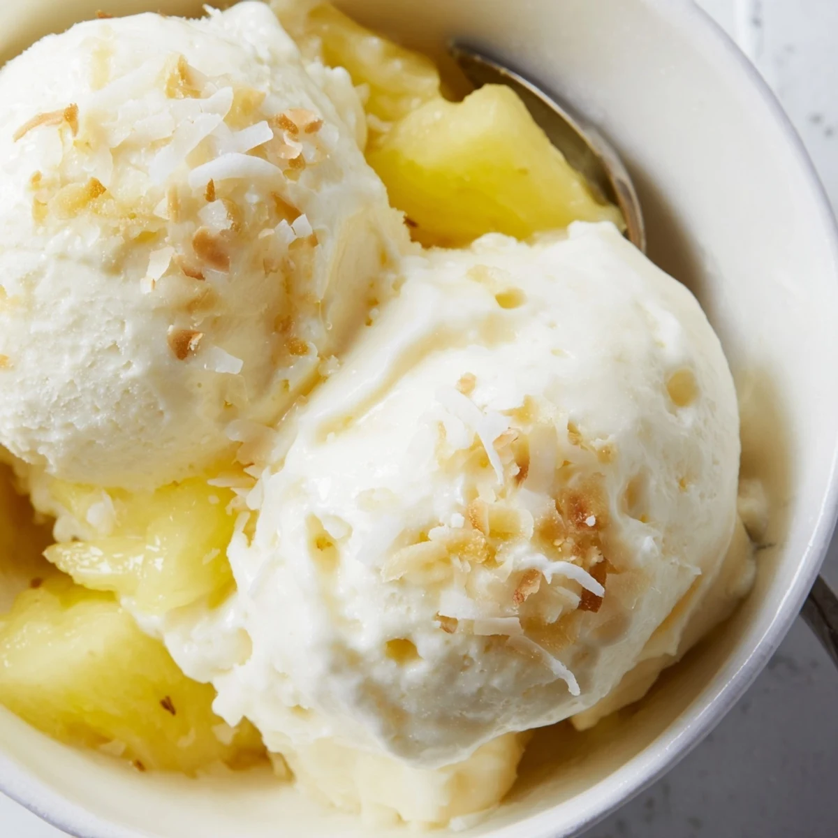 Creamy Pineapple Ice Cream scoops melting slightly, bright tropical aroma, chilled bowl