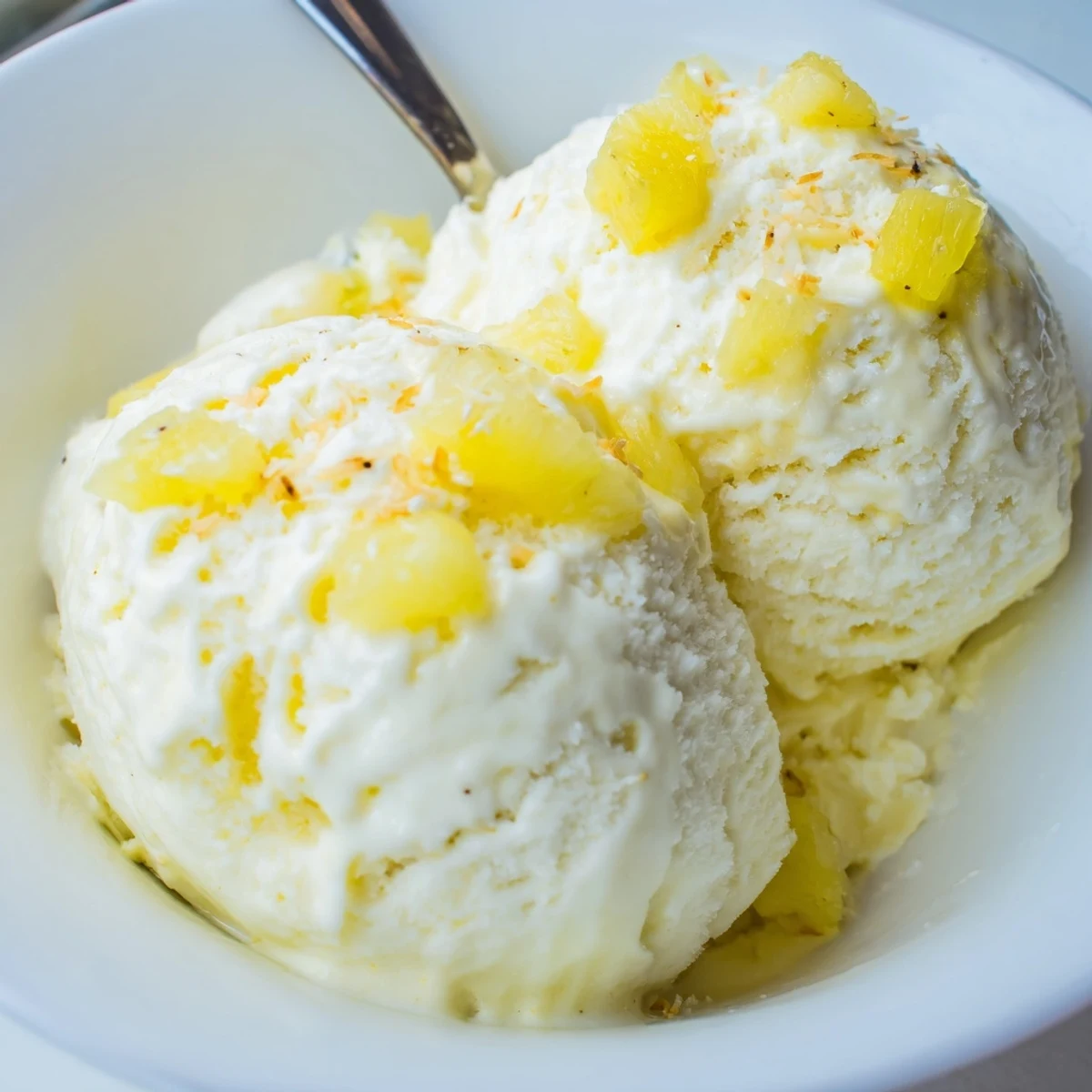 Homemade Creamy Pineapple Ice Cream with tangy pineapple chunks, toasted coconut sprinkle