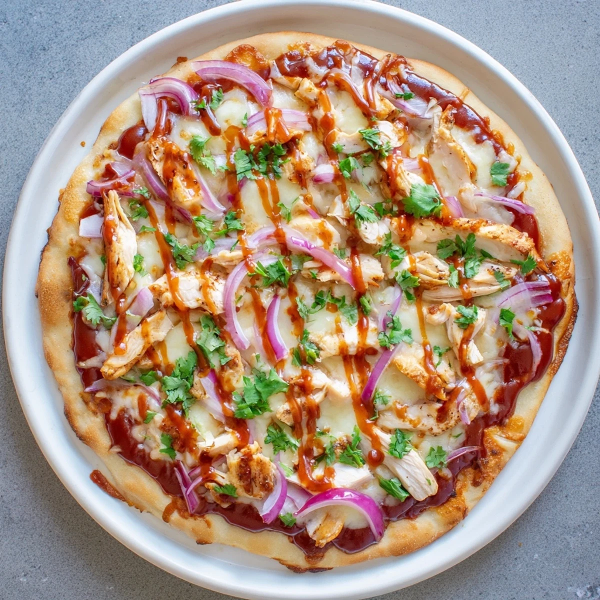 Golden grilled BBQ chicken pizza featuring melted mozzarella, smoked gouda, and fresh cilantro atop a crispy fire-kissed crust