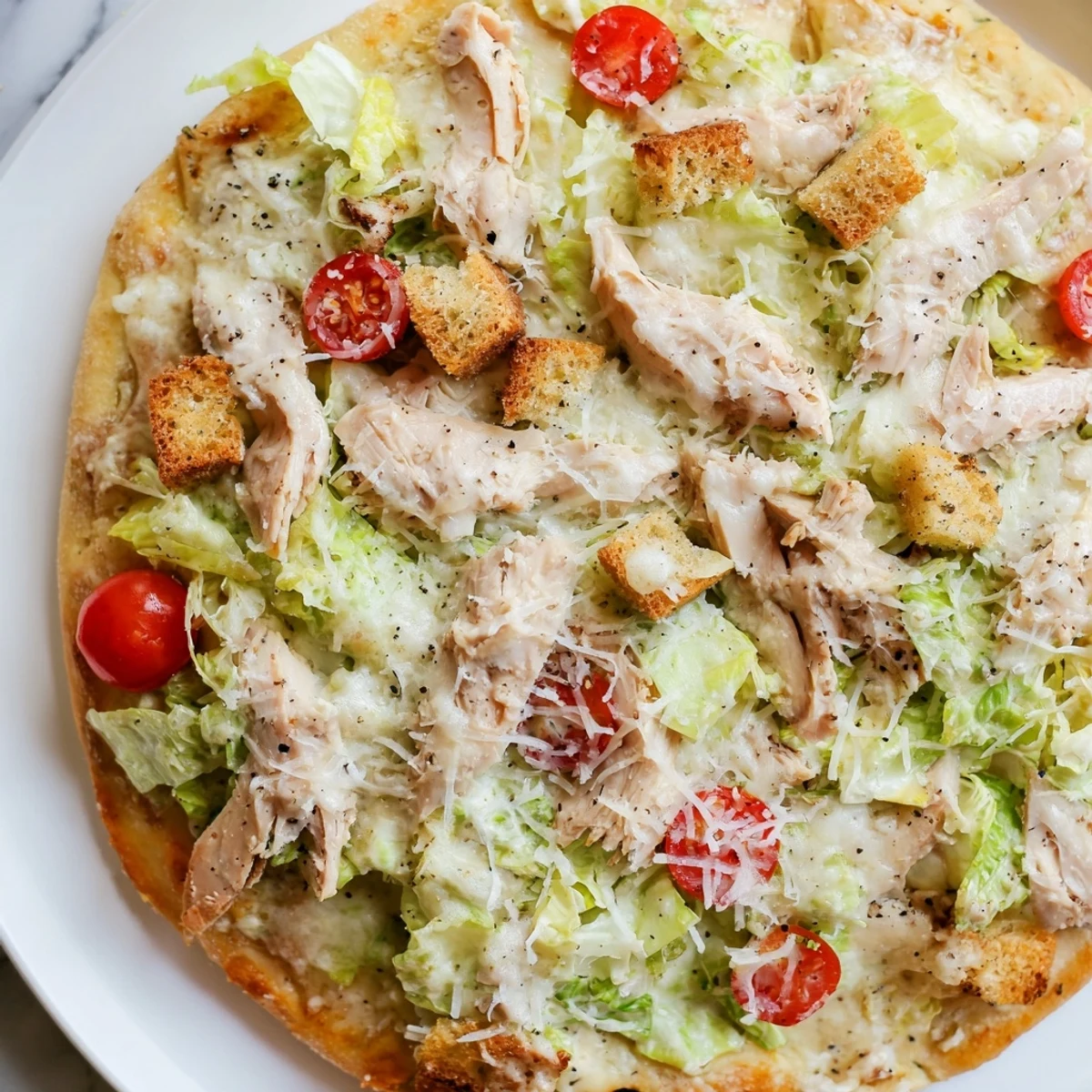 Chicken Caesar salad pizza featuring juicy chicken breast topped with fresh lettuce and creamy dressing