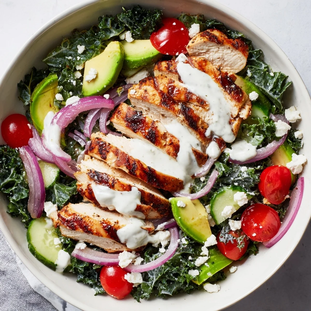 Colorful marinated kale and chicken bowl with fresh vegetables and creamy homemade dressing