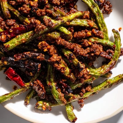 Charred green beans and seasoned minced beef in a vibrant stir-fry, ready to be scooped into a bowl for a spicy weeknight dinner. 