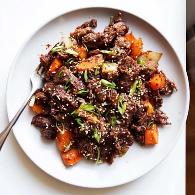 Korean Style Pot Roast rests on a platter with caramelized onions and glistening sauce, ready for a family-style main dish.